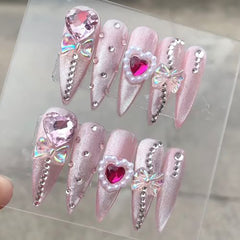 VIBEFICANT GLAZE pink cat eye long stiletto press-on nails with rhinestones and bows.
